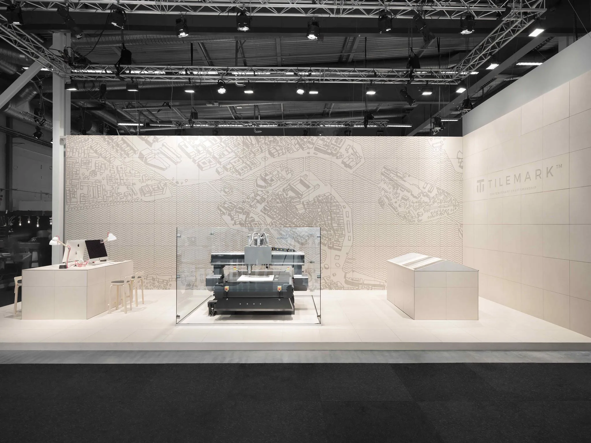 Tilemark exhibition booth with the carving machine behind glass, in front of a wall of carved tiles